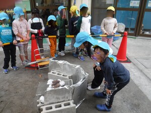 かまどで芋を焼いている様子を見る園児たち