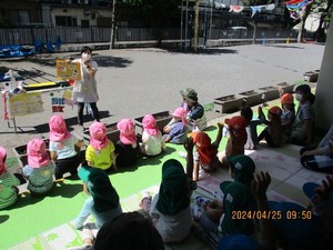 写真:ベランダで保育士の話を聞く子どもたち