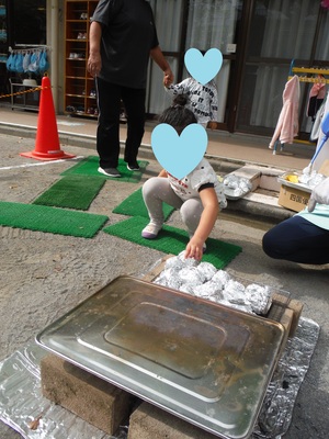 かまどの上に敷いた網の上にお芋を投げ入れている様子