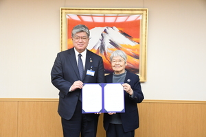 協定書を持つ坂口代表理事(右)と坂本区長(左)